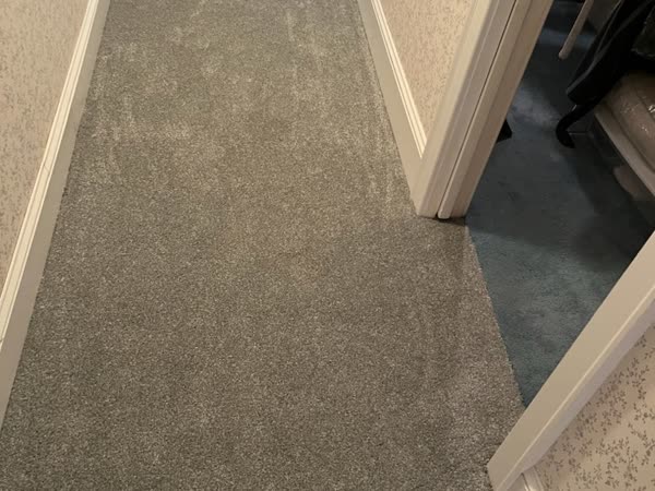 Completed grey carpet installation through a hallway and closet doorway