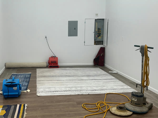 Hardwood floor being refinished with a buffer and air mover running