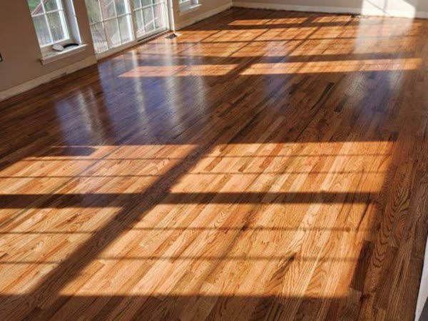 Refinished hardwood floor in a sunlit empty room after restoration