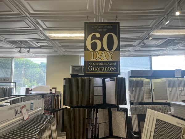 The 60 Day No Questions Guarantee sign above the carpet display
