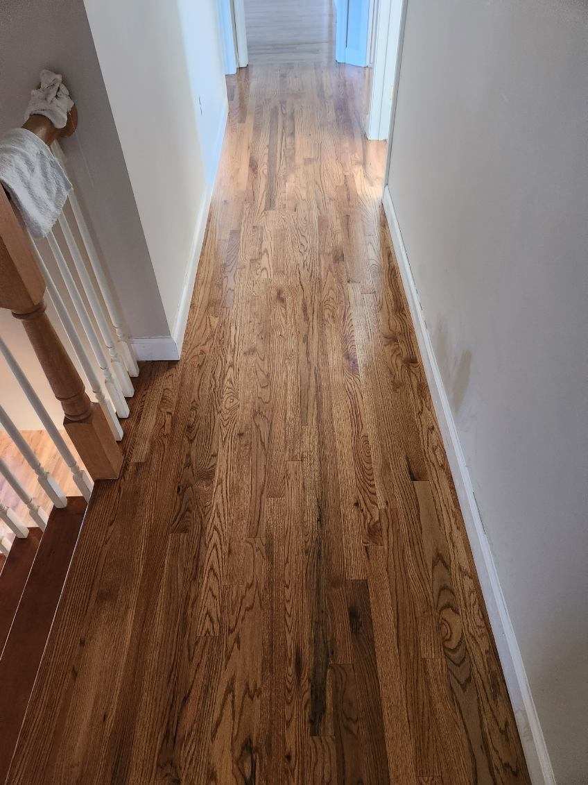 Refinished hardwood staircase and hallway with a fresh glossy finish